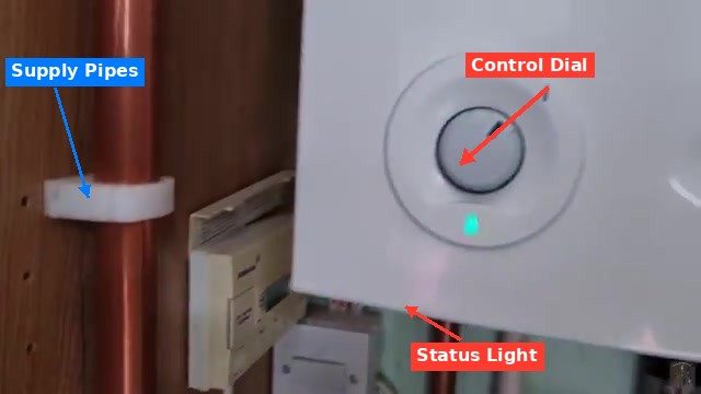 Boiler control dial and copper supply pipes with green status indicator light